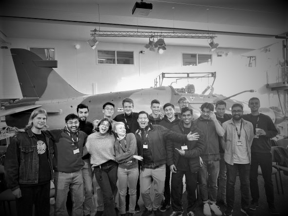 a large group of people smiling are standing in front of an aeroplane